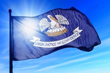 Louisiana state flag flying in a blue sky.