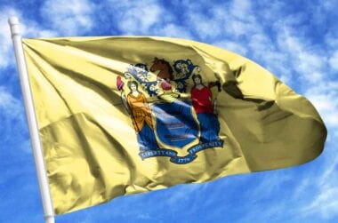 New Jersey state flag flying in a blue sky.