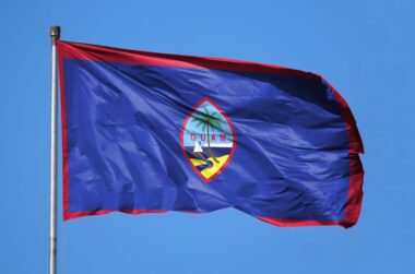 Guam flag flying in blue sky.